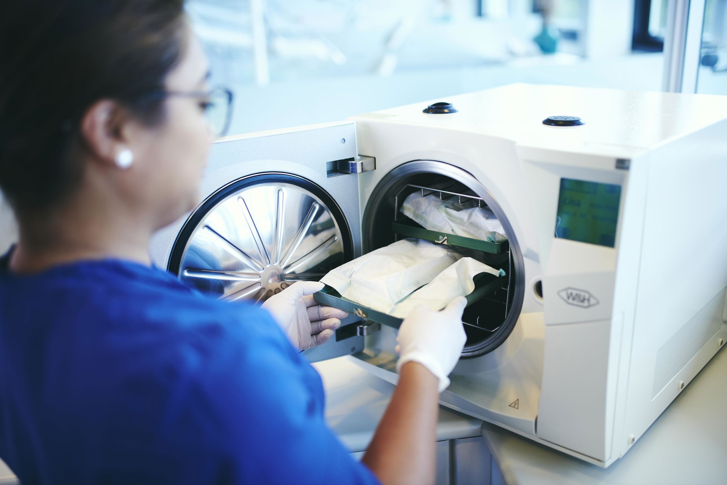 En elev på tandklinikassistentuddannelsen tager sterile pakker med instrumenter ud fra steriliseringsmaskinen i skolens tandklinik.