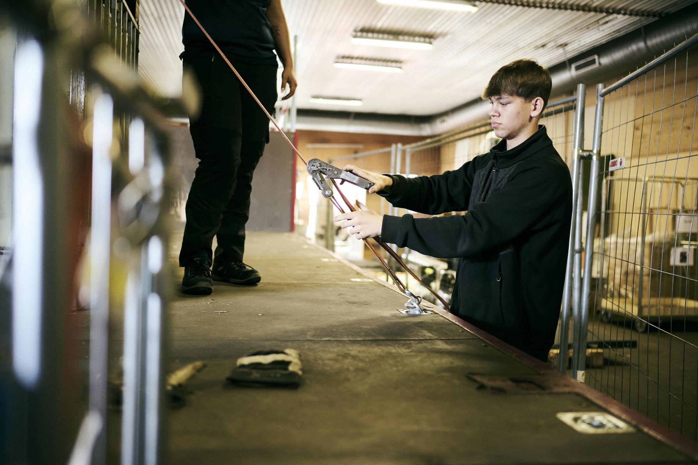 En elev på vejgodstransportuddannelsen er ved at surre godset fast på ladet af en lastbil.