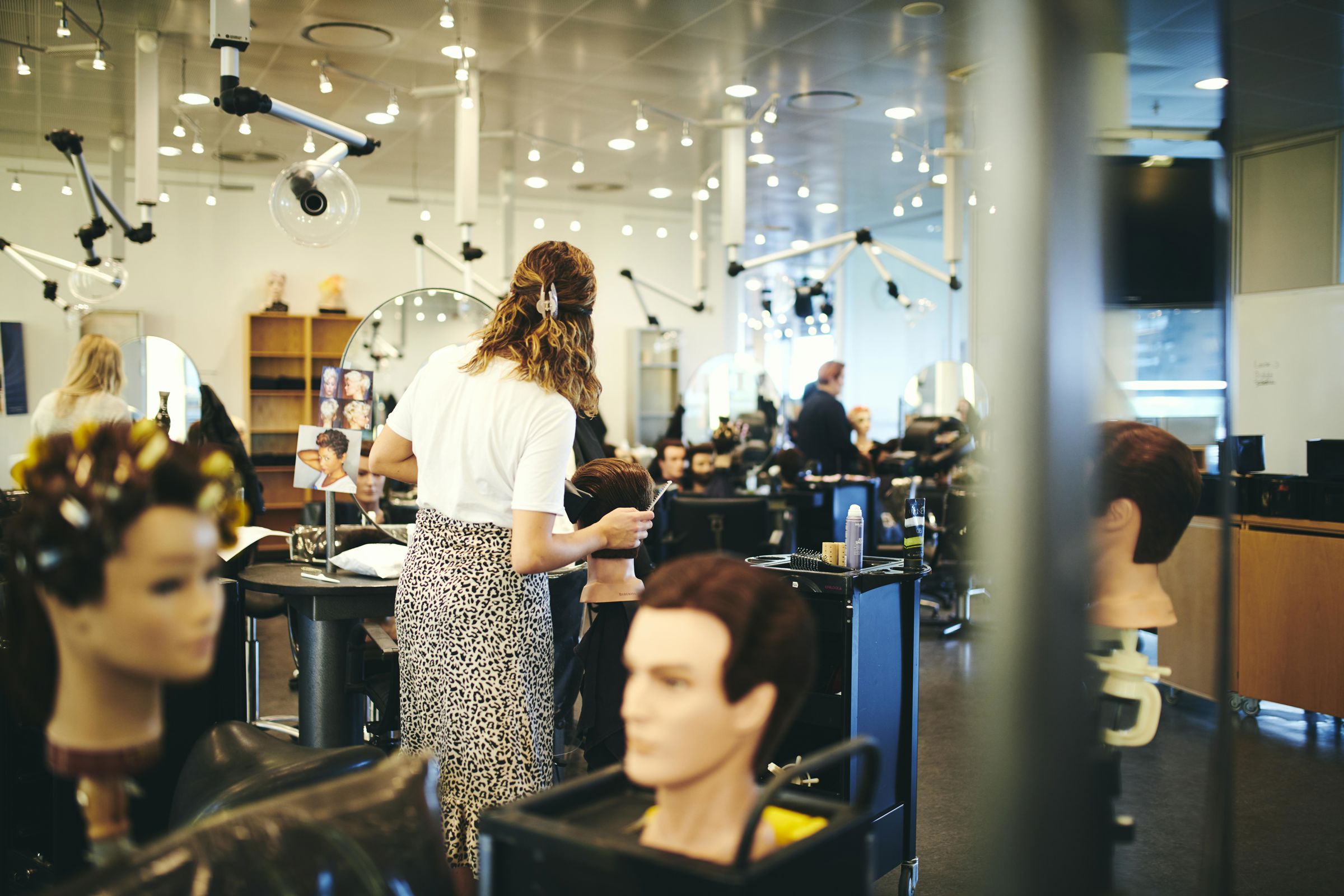 Frisørelev på Hansenberg ordner hår på et øvelseshoved i skolens frisørsalon.
