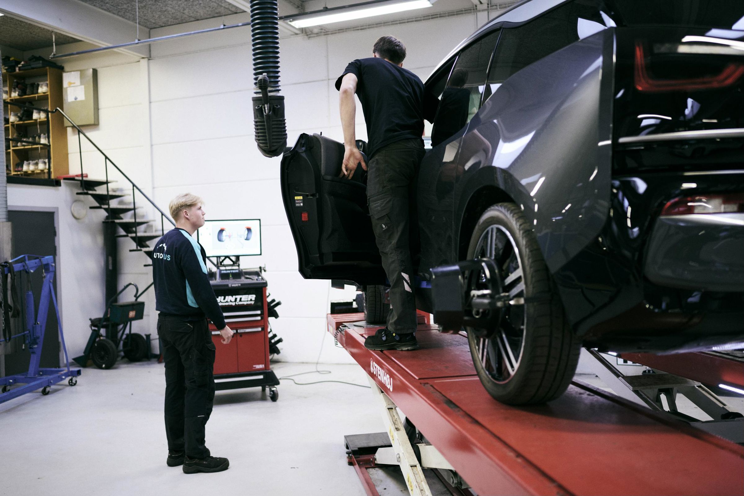 Et par personvognsmekanikerlærlinge bruger et hjulsporeanlæg på Hansenbergs autoværksted.